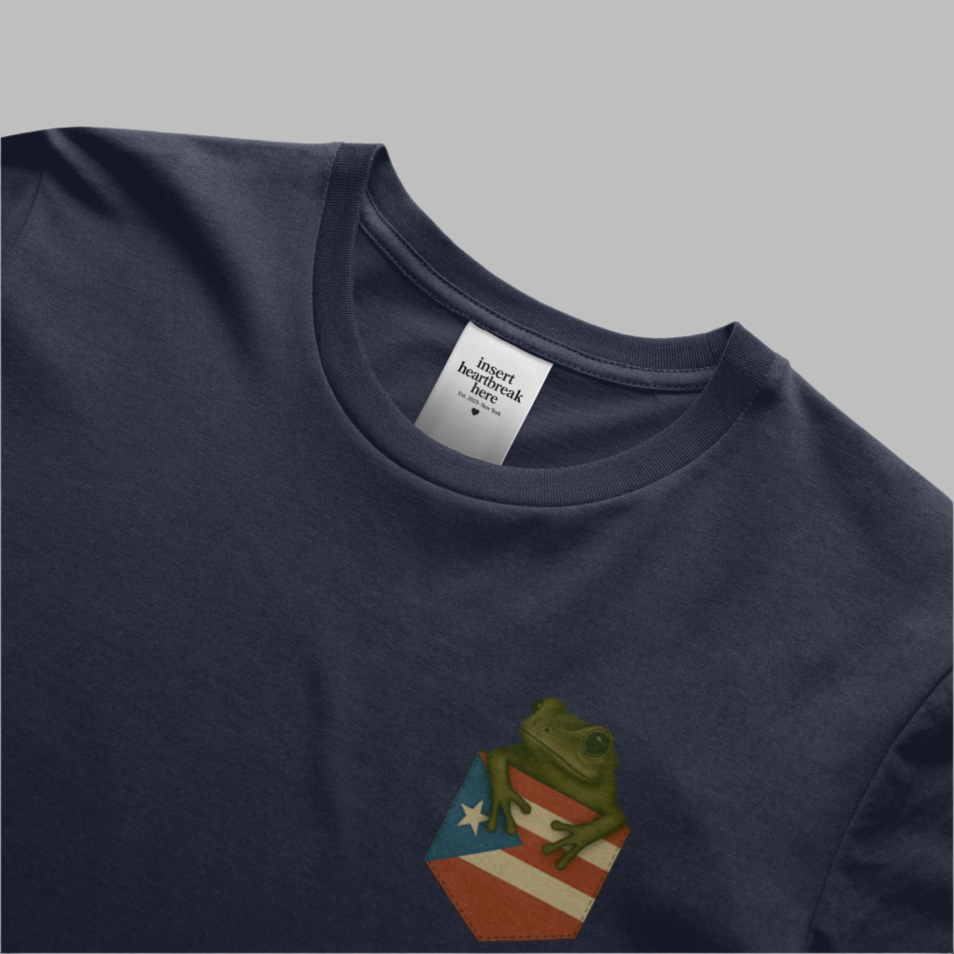 Navy blue t-shirt with a small graphic of a frog on a flag design, visible brand label.