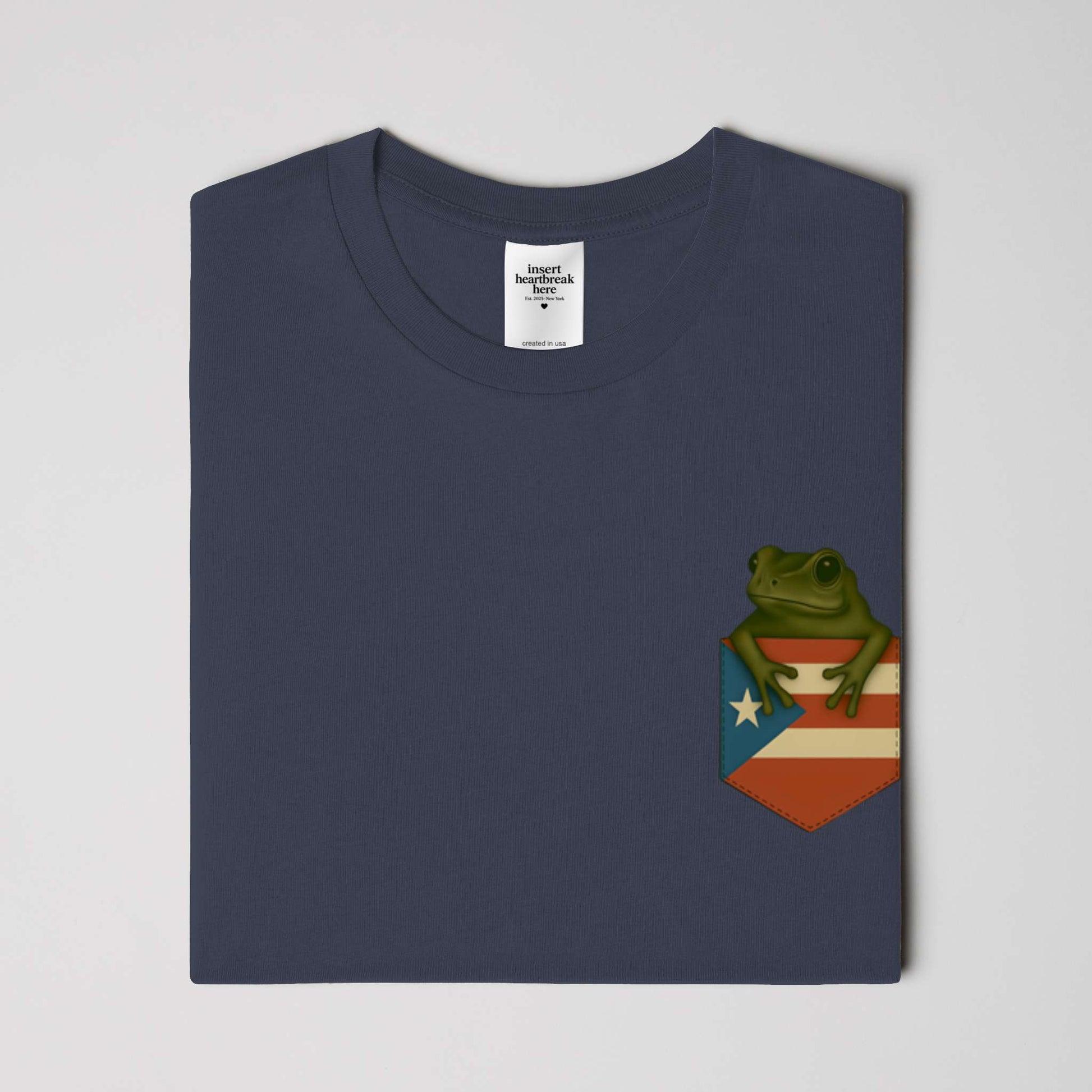 Navy blue t-shirt with a frog design on a flag patch against a light gray background